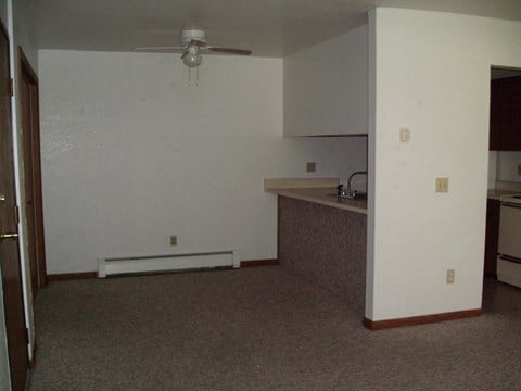 an empty room with a kitchen and a ceiling fan